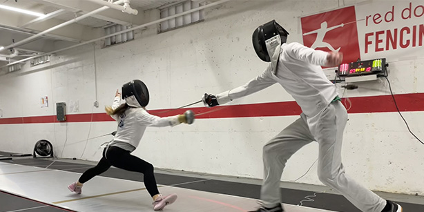 Two individuals fencing with their masks on